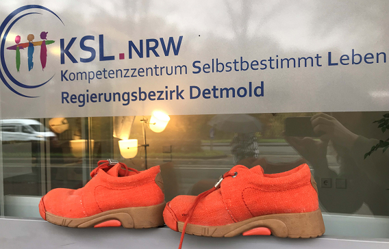 orangenes Schuhpaar vor KSL OWL Schild