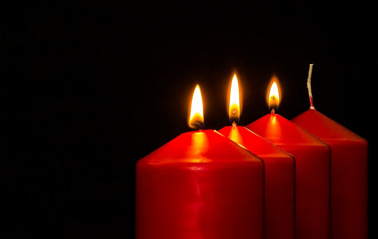 Das bild zeigt vier rote Kerzen, von denen drei brennen.