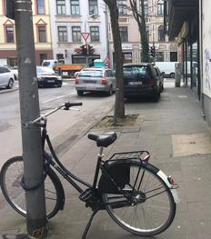 Ein Fahrrad steht quer auf dem Gehweg.