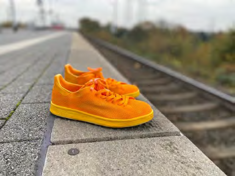 orangenes Schuhpaar an der Bahnsteigkante