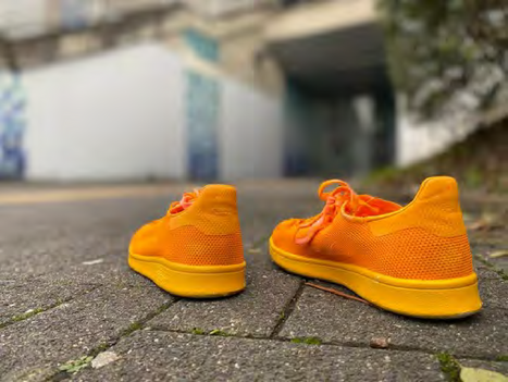 orangenes Schuhpaar vor einem Hauseingang