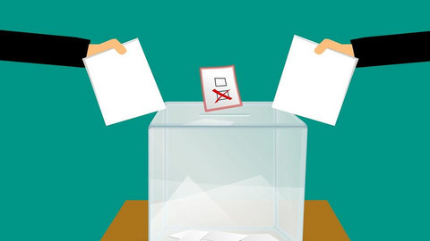 In eine Wahlurne werden zwei Stimmzettel gesteckt.