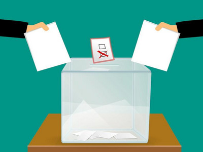 In eine Wahlurne werden zwei Stimmzettel gesteckt.