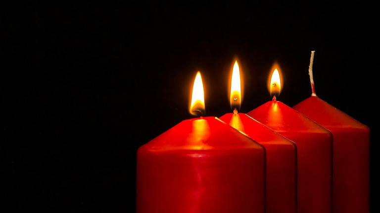 Das bild zeigt vier rote Kerzen, von denen drei brennen.
