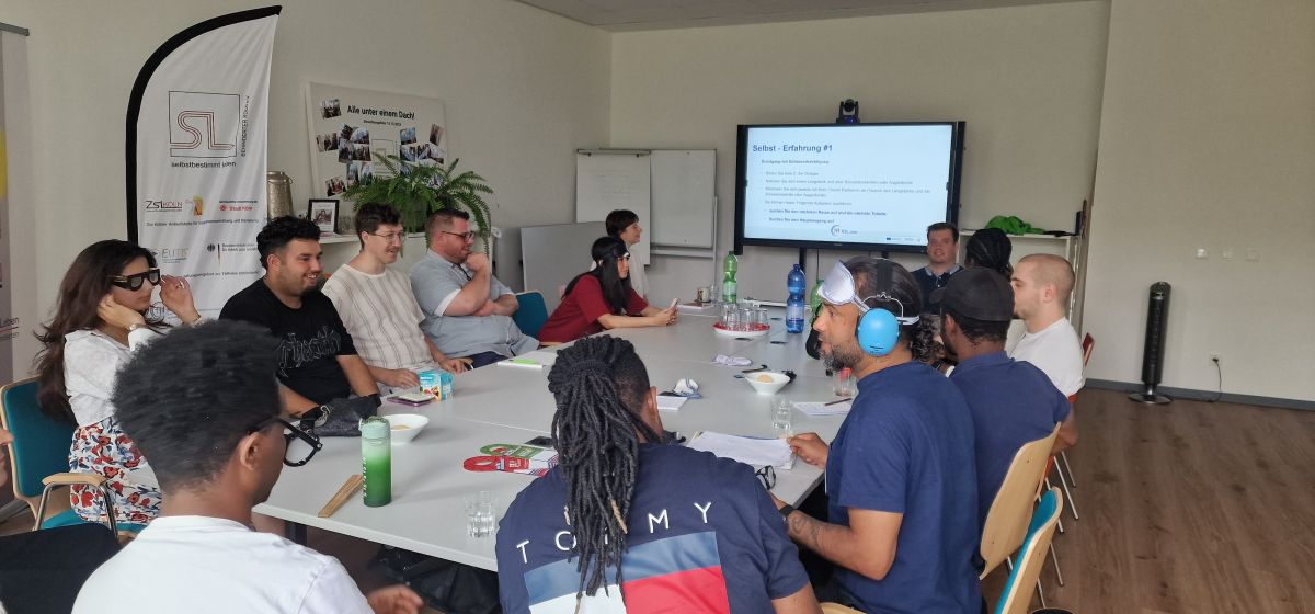 Die Pflegeschüler*innen sitzen am Meetingtisch und schauen die Präsentation vom KSL Köln und probieren die Brillen und Augenmasken aus.