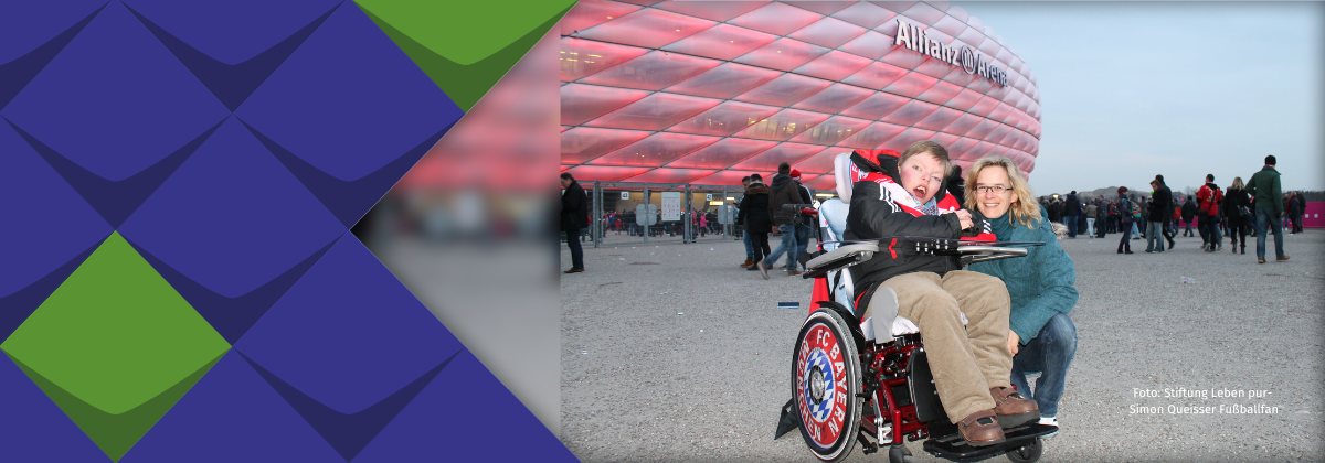 Allianz-Arena und Fußballfan, Stiftung Leben pur Vor der Allianz-Arena in München steht ein Rollifahrer, der sich offensichtlich freut, daneben hockt seine Mutter.