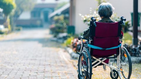 eine Person sitzt in einem Rollstuhl und steht mit dem Rücken zum Betrachter