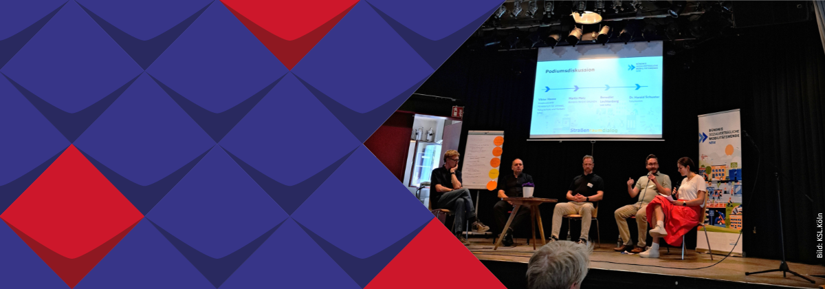 Fünf Personen sitzen nebeneinander auf der Bühne; eine spricht in ein Mikrofon. Im Hintergrund steht "Podiumsdiskussion" und ein Banner vom Bündnis sozialverträgliche Mobilitätswende NRW.