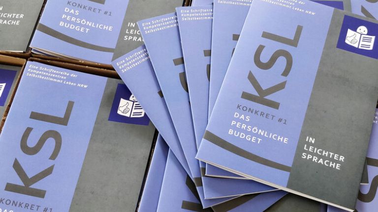 Mehrere Hefte KSL Konkret zum Persönlichen Budget in Leichter Sprache liegen nebeneinander.