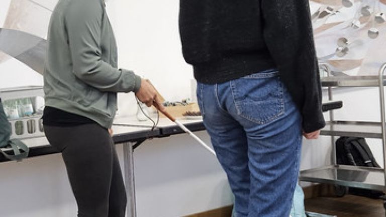 Personen erkunden mit einem Langstock und Simulationsbrille das Gebäude